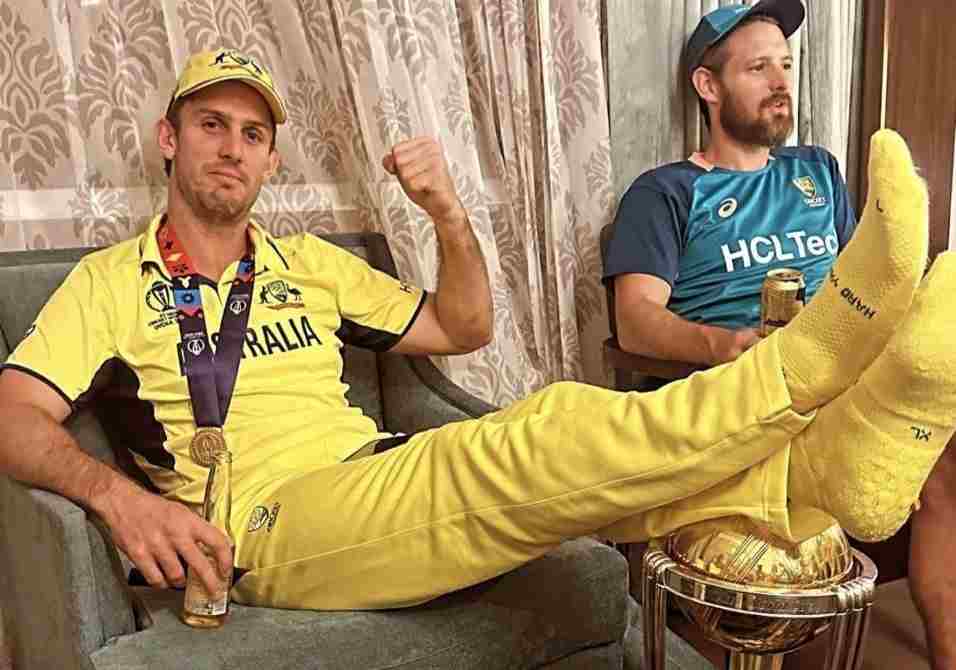 Mitchell Marsh reclining on a couch with his feet casually resting atop the revered World Cup trophy