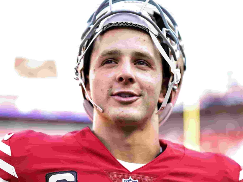 Brock Purdy in a San Francisco 49ers jersey, throwing a pass during a football game.